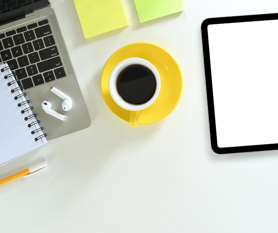 photo of yellow coffee cup and saucer with some post it notes and a laptop